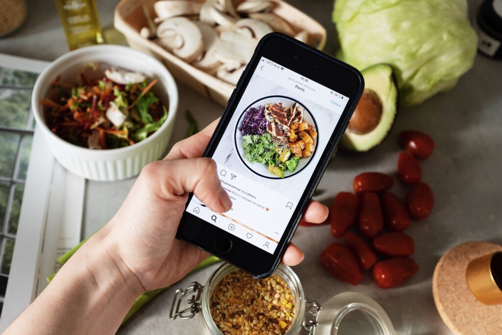mão segurando um android e fotografando uma mesa de comida para identidade visual no Instagram